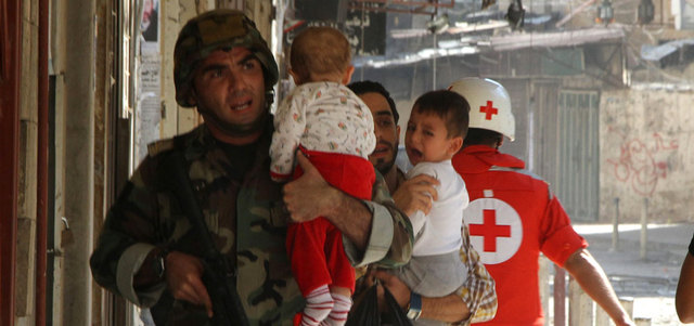 جندي لبناني يحمل طفلاً خلال إخلاء المدنيين من منطقة الاشتباكات مع المسلحين وسط طرابلس. إي.بي.إيه