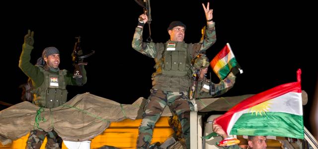 مقاتلون من «البشمركة» يرفعون شارة النصر ويهتفون عند مغادرتهم أطراف بلدة سروج التركية باتجاه عين العرب. أ.ب