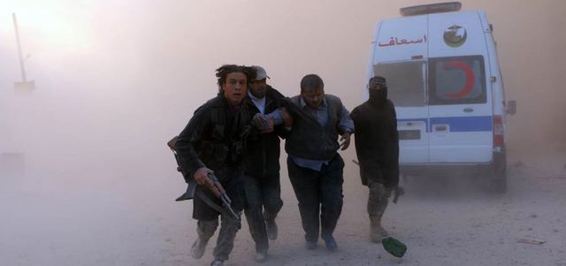 مقاتلون يساعدون رجلاً أصيب بإلقاء القوات النظامية برميلاً متفجراً على مبنى في شارع المواصلات بحي الشعار في حلب. أ.ف.ب