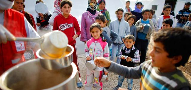 لاجئون أكراد فروا من بلدة الغجر السورية قرب عين العرب يقفون في طابور للحصول على الطعام في مخيم ببلدة سروج التركية. رويترز