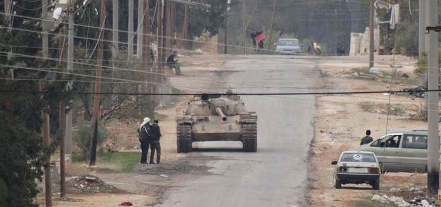 عناصر من «لواء القادسية» يتحركون في الشارع خلال اشتباكات مع القوات النظامية بمنطقة سيفات قرب حلب. أ.ف.ب