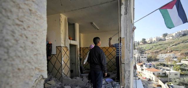 فلسطيني يرفع العلم فوق منزل الشهيد عبدالرحمن الشلودي في سلوان الذي هدَّمته قوات الاحتلال.

أ.ف.ب