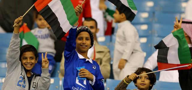 أطفال عاشقون للكرة الخليجية يرفعون الأعلام الإماراتية في الرياض خلال مباراة الأبيض مع العراق. تصوير: إريك أرازاس