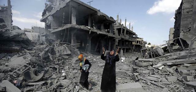 فلسطينيتان وسط بيتهما المدمر الذي ينتظر إعادة الإعمار. أ.ف.ب