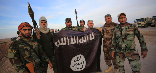 مقاتلون موالون للحكومة يحملون علم «داعش» بعد طرد «التنظيم» من بلدة جلولاء.  رويترز