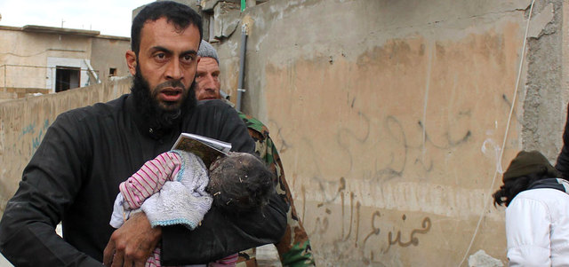 سوري يحمل جثة طفل قتل بقصف للقوات السورية على مدينة الرقة. أ.ف.ب
