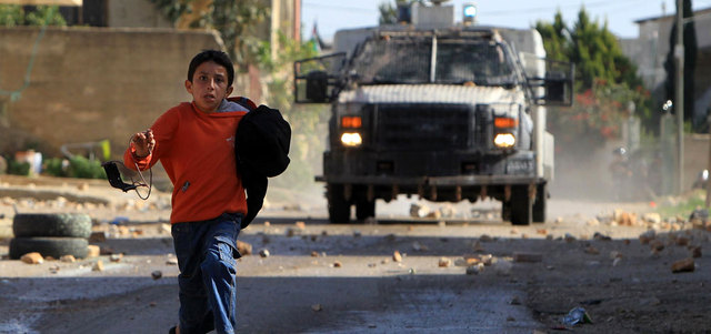 سيارة عسكرية للاحتلال تطارد طفلاً فلسطينياً خلال مواجهات بالقرب من نابلس. أ.ف.ب