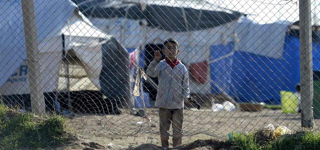 طفل يزيدي في مواجهة جدار يطوق مخيماً للنازحين قرب أربيل.  إي.بي.إيه