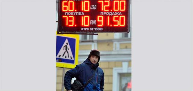 رجل يقف تحت لوحة تظهر فيها أسعار العملات إزاء الروبل المتهاوي. أ.ف.ب