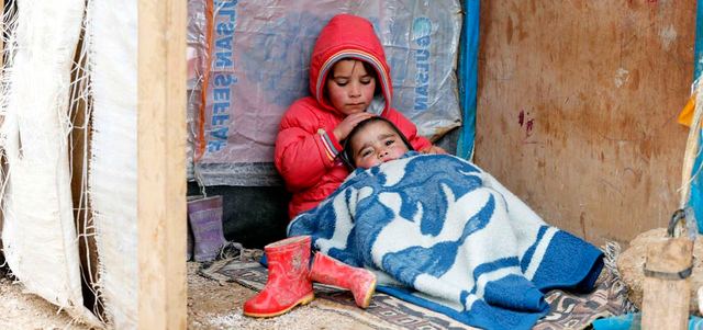 طفلة سورية تحتضن شقيقها في خيمة مؤقتة في بر الياس بوادي البقاع شرق لبنان.  رويترز