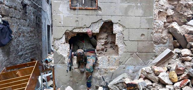 مقاتل من الجيش الحر يخرج من ثقب في جدار خلال اشتباكات مع النظام في حلب القديمة.  رويترز