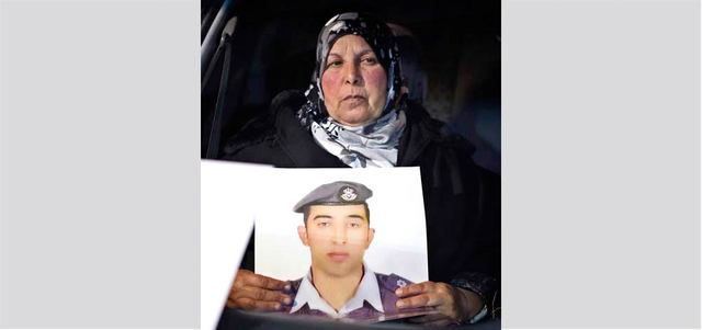 والدة الطيار الأردني معاذ الكساسبة تحمل صورة ابنها خلال وقفة احتجاجية أمام مقر رئاسة الوزراء.  أ.ب