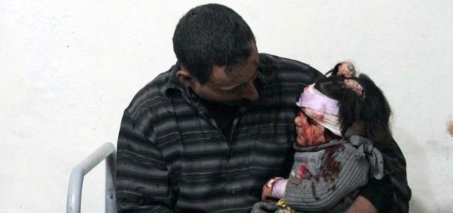 سوري يحمل ابنته المصابة بغارات للنظام أمس. رويترز