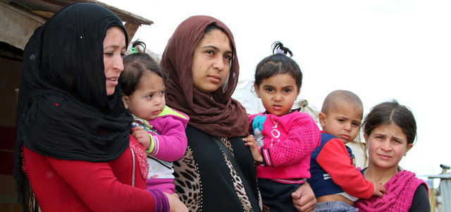 لاجئات سوريات يحملن أطفالاً في مخيم على مشارف مدينة بعلبك شرق لبنان.  أ.ف.ب
