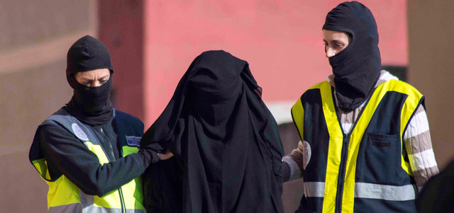 عنصران من الشرطة الإسبانية يعتقلان امرأة يشتبه في أنها تعمل في شبكة لتجنيد النساء للقتال مع «داعش» في سورية. رويترز