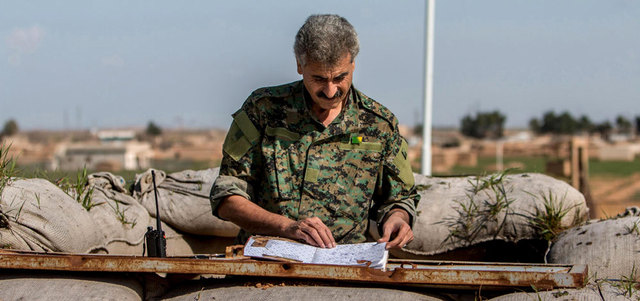 مقاتل كردي يتفقد وثائق  خلفها «داعش» في حاجز بتل خميس في ريف الحسكة بعد سيطرة الأكراد على المنطقة. أ.ف.ب