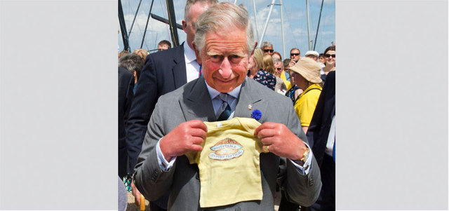 تشارلز يبدو سعيداً وهو يعرض ثياب حفيده. أرشيفية