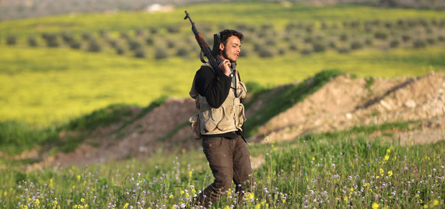 مقاتل من الجيش السوري الحر يحمل سلاحه في حقل على خط المواجهة مع قوات النظام ببلدة مورك بريف حماة. رويترز