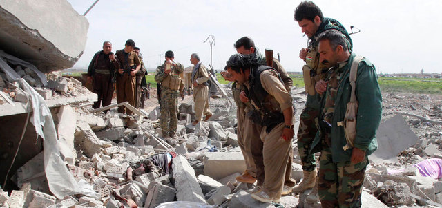 مقاتلون من قوات البشمركة الكردية يشاهدون جثثاً لعناصر من «داعش» قتلوا خلال المواجهات في ضواحي تل ورد غرب كركوك.  رويترز