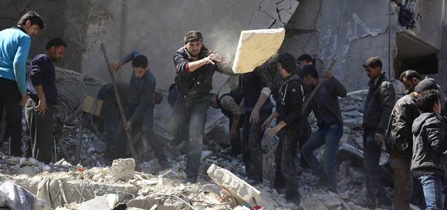 سوريون يبحثون عن ناجين تحت أنقاض مبنى تهدم بغارة للقوات السورية على دوما شرق دمشق.  أ.ف.ب