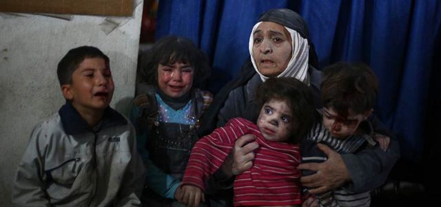 امرأة سورية تحمل أطفالاً ينتظرون تلقي العلاج بعيادة في دوما شرق العاصمة دمشق في أعقاب غارات جوية للقوات الحكومية أمس. أ.ف.ب