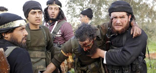 مقاتلون من حركة «أحرار الشام» يساعدون زميلاً لهم أصيب باشتباكات مع قوات النظام شمال غرب مدينة إدلب. رويترز