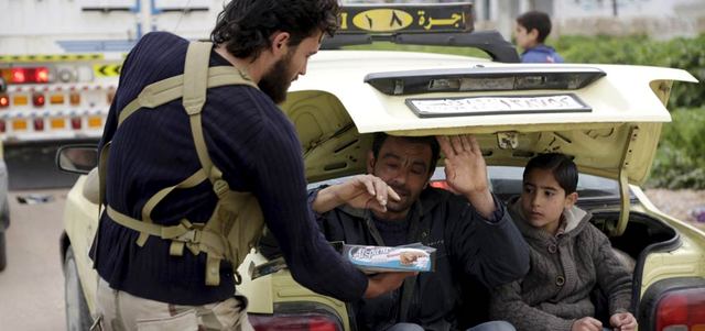 مقاتل من المعارضة يوزّع الشوكولا على مدنيين فارّين من مدينة إدلب خوفاً من غارات النظام السوري. رويترز