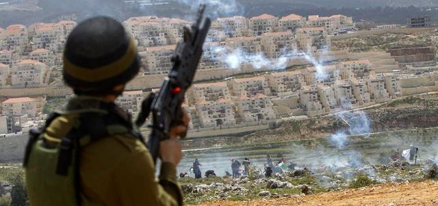 جندي إسرائيلي يطلق الغاز المسيل على فلسطينيين في بلدة وادي فوكين بالضفة الغربية قرب إحدى المستوطنات في ذكرى يوم الأرض. إي.بي.إيه