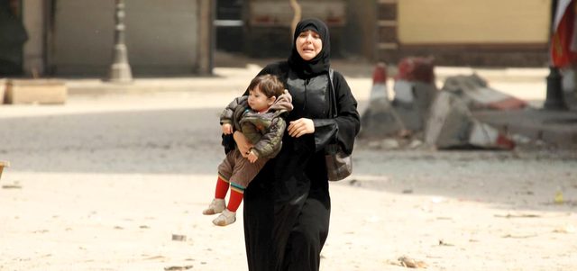 امرأة تبكي وهي تحمل طفلها هرباً من قصف نفذته القوات النظامية على مسجد في مدينة إدلب. رويترز