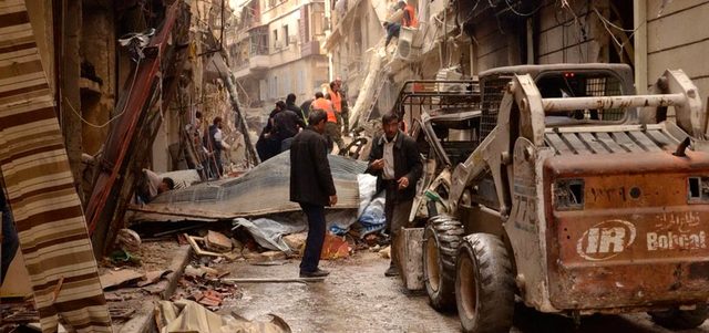 صورة بثتها «سانا)» لمدنيين وعسكريين يتفقدون أثار القصف على حي السليمانية بحلب. أ.ب
