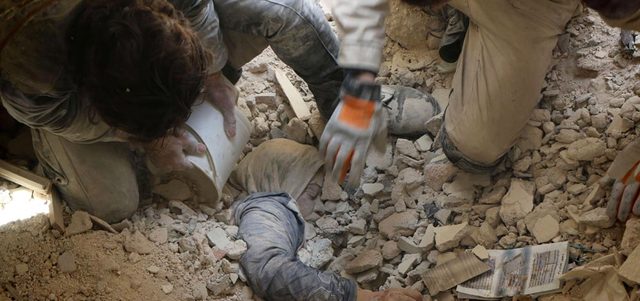 مسعفان يحاولان إخراج جثة امرأة من تحت أنقاض مبنى تدهم ببرميل متفجر ألقته القوات النظامية على حي بستان القصر في حلب. أ.ف.ب