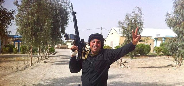 عنصر من قوة الرد السريع يرفع علامة النصر في منطقة الحصيبة وهو في طريقه إلى خط المواجهة ضد «داعش» في الرمادي.  أ.ب