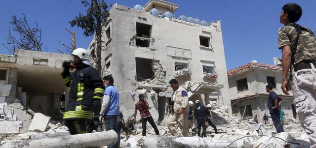 عناصر من الدفاع المدني يبحثون عن ناجين في مركز للهلال الأحمر بحي الصاخور في حلب الذي استهدفته القوات النظامية ببرميل متفجر. رويترز