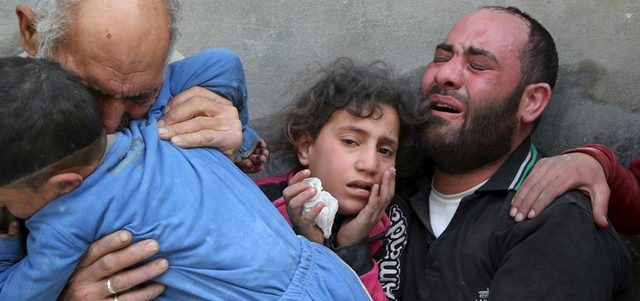 عدد من أفراد عائلة يبكون فقدان ذويهم جراء إلقاء القوات النظامية برميلاً متفجراً على حي الفردوس في حلب.  رويترز