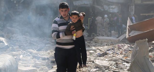 شاب يحمل طفلاً ويفرّ به من موقع تهدم ببرميل متفجر ألقته القوات النظامية على حي الصالحين في مدينة حلب. رويترز