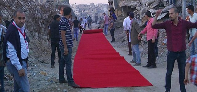 نسجت الستارة الحمراء التي غيرت ملامح الحي المدمر، على أيدي فنانين ومخرجين من أبناء غزة المحاصرة ليسير عليها أصحاب المنازل المدمرة في حي الشجاعية. الإمارات اليوم