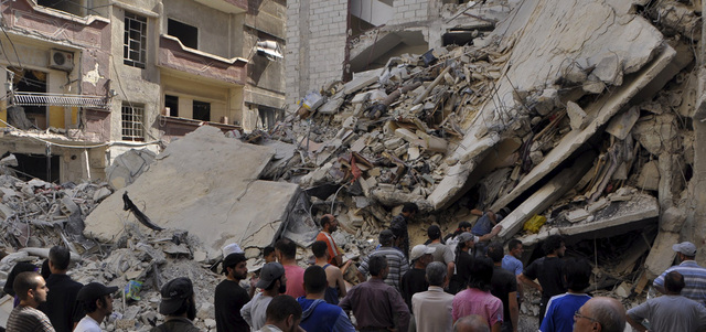 مدنيون يبحثون عن ناجين تحت أنقاض مبنى تهدم بقصف للنظام على مخيم اليرموك. رويترز