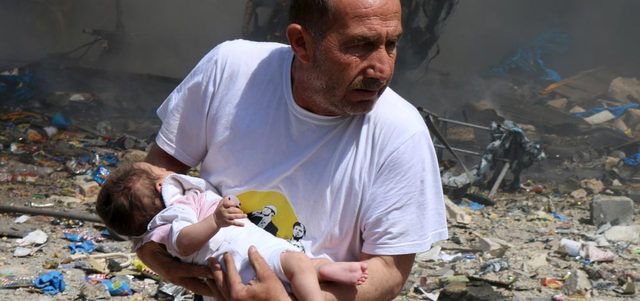 رجل يحمل طفلاً نجا من برميل متفجر ألقته القوات النظامية على مدينة حلب القديمة. رويترز