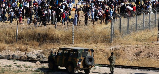 مئات اللاجئين ينتظرون على الجانب السوري من الحدود للدخول إلى تركيا من معبر أكشاكله بمقاطعة شانلي أورفا هرباً من المواجهات بين الأكراد و«داعش». أ.ب
