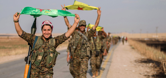مقاتلة من «وحدات حماية الشعب» الكردية ترفع الراية الحزبية فرحاً في مدينة تل أبيض السورية الحدودية مع تركيا بعد طرد «داعش» منها.  رويترز