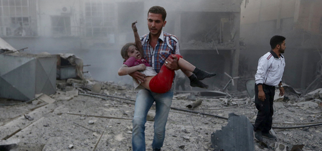 شاب يحمل فتاة أصيبت بقصف عنيف من قبل القوات النظامية على مدينة دوما بريف دمشق. رويترز