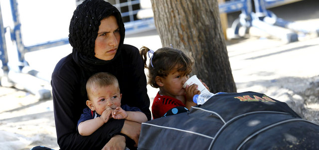 سورية فرت من مدينة تل أبيض تنتظر مع طفليها عند معبر أقجة قلعة التركي للسماح لها بالعودة إلى المدينة. رويترز