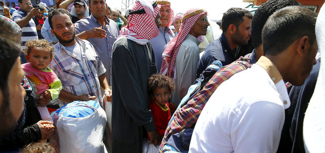 لاجئون سوريون ينتظرون أمام البوابة الحدودية في معبر أقجة قلعة التركي للعودة إلى مدينة تل أبيض. رويترز