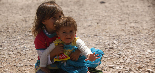 طفلان عراقيان فرا مع عائلتهما هرباً من «داعش» في الموصل، يجلسان على الأرض على مشارف مدينة النجف جنوب بغداد. رويترز