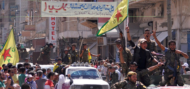 عناصر من «وحدات حماية الشعب» الكردية في موكب يجوب مدينة القامشلي بعد عودتهم من محاربة «داعش» في تل أبيض على الحدود مع تركيا.  أ.ف.ب