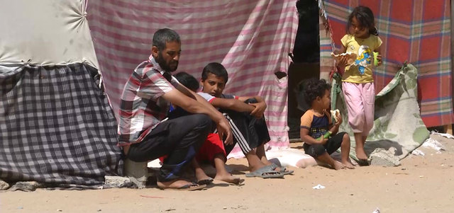 أطفال من العائلتين يجلسون خارج الخيمة بإحدى الطرقات في حي تل الهوى.   الإمارات اليوم