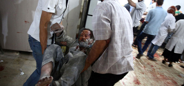 شابان يحملان عجوزاً إلى مستشفى ميداني بعد إصابته بغارة للقوات النظامية أول من أمس على مدينة دوما بريف دمشق. أ.ف.ب