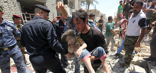 شاب يحمل طفلاً تم إخراجه من تحت أنقاض منزل تهدم بسقوط قنبلة من مقاتلة عراقية على حي النعيرية في بغداد.  رويترز