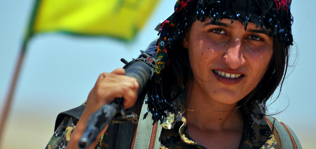 مقاتلة من «وحدات حماية الشعب» تحمل سلاحها في بلدة عين عيسى، شمال الرقة معقل «داعش»، بعد سيطرة الأكراد على البلدة. أ.ف.ب