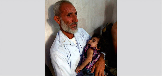 رجل يحتضن طفلاً في مستشفى ميداني بعد إصابته بغارة للقوات النظامية على مدينة دوما بريف دمشق. أ.ف.ب